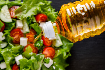 sunflower oil in a bottle is added to the salad, top view 