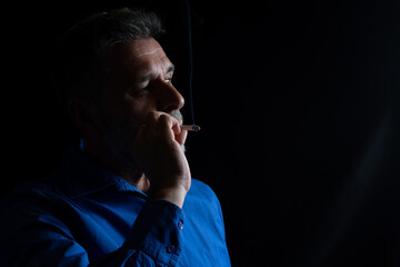 A mature handsome white bearded man smokes a cigarette