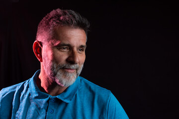 Neon light studio close-up portrait of serious man model with  beard in dark studio