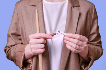 Woman teacher holding broken cigarette on studio blue background, close-up