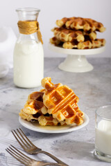Close-up of a plate with golden waffles, paired with milk, presented on a marble surface.
