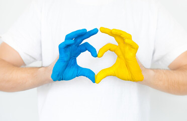 Ukraine against the war. Russia's invasion of Ukraine, a request for help to the world community. Man on a white background with hands in the shape of a heart, painted in yellow and blue