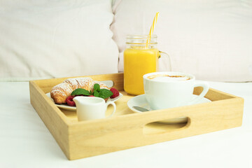 Coffee, orange juice and a croissant on a wooden stalk