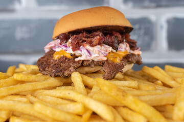 Smash burger with coleslaw sauce, bacon on top of a potato bed