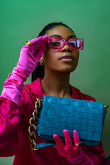 Fashionable elegant Black woman wearing trendy pink sunglasses, fuchsia color blouse, gloves,...
