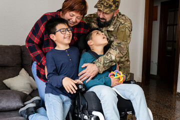family returned home to dad in the army,child in wheelchair with disability - family embrace -