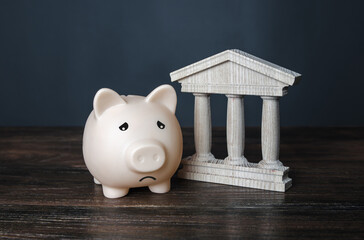 Sad piggy bank and state building. crisis, depletion of savings and bankruptcy. Financial default....