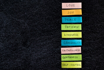 Colorful list of the fruits of the Holy Spirit (love, joy, peace, patience, kindness) isolated on dark background with copy space. Top view, a close-up. Christian fruit from Galatians Bible Book.
