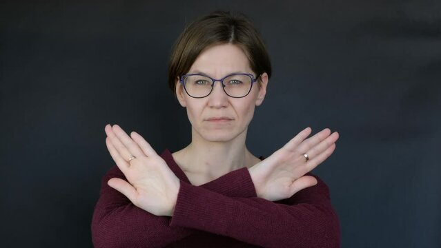 Thoughtful serious woman with crossed arms showing her objection, protest, stop sign , black background