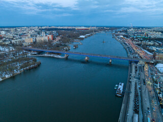 Duża rzeka widziana z drona podczas zachodu słońca, Warszawa, widoczne zabudowania i brzeg, mosty - obrazy, fototapety, plakaty