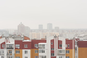 view from the window of a new building on the snow-covered roofs of houses in the old part of the foggy city