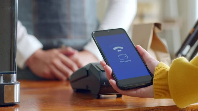 Customer using smartphone for NFC payment at cafe restaurant, cashless, contactless technology and money transfer concept