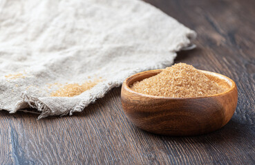 Cane sugar in a wooden bowl and on coarse burlap.