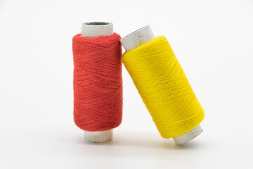 yellow and red color yarn or spool thread over white background