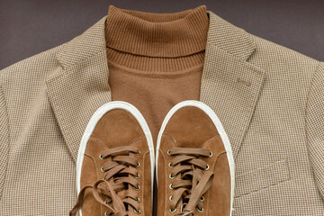 Men brown suede sneakers combined with light beige blazer and sweater. Top view.