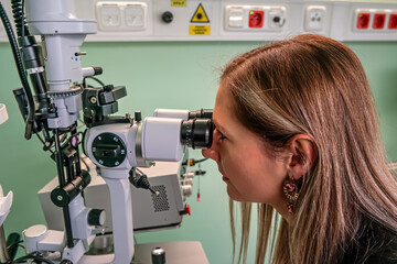 Young woman looking into eye examination machine in optometrist ambulance