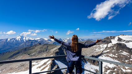 Woman enjoying the panoramic view from Hoher Sonnblick on mountain ranges of High Tauern Alps in...