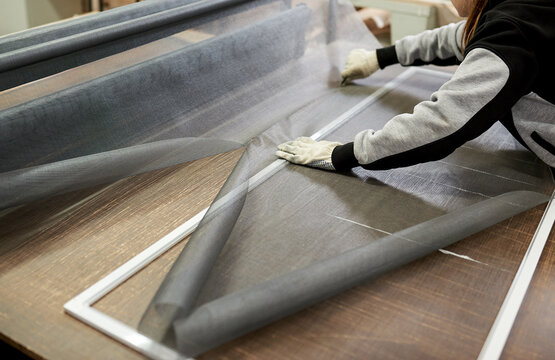 Factory shop for the production of mosquito nets. Hands of a worker assembling the structure.