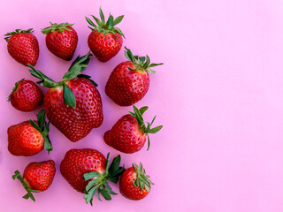Fresh red strawberries with green leaves on pink background with copy space