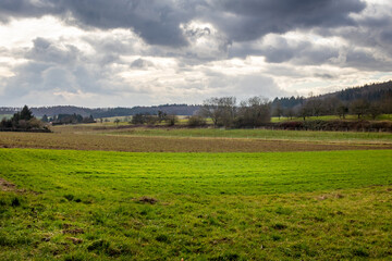 Fototapeta premium meadow and field landscape in southern Germany with dramatic clouds after winter storm