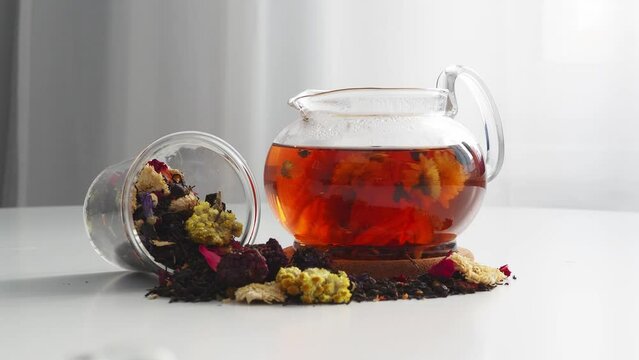 Tea in a glass teapot is spinning in a circle. Brew tea collection from flowers in a teapot. A scattering of dry tea leaves. tea movement
