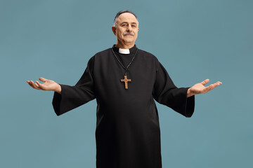 Mature priest spreading arms and looking at camera