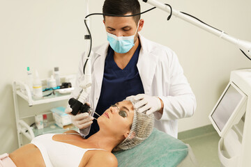 Doctor dermatologist and woman client during laser skin resurfacing treatment