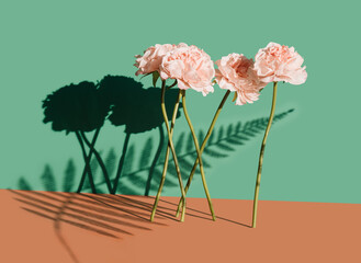 Artificial pink flowers against the green and orange pastel background. Surreal spring concept.