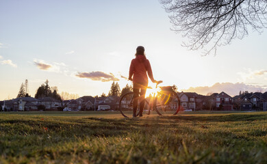 Adventurous Woman Standing with a bicycle at a Park in Modery City Suburbs.