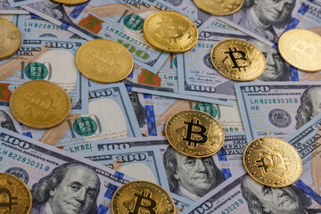 yellow bitcoin coins scattered over US dollar paper banknotes, closeup with selective focus