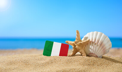 Fototapeta na wymiar Tropical beach with seashells and Italy flag. The concept of a paradise vacation on the beaches of Italy and Sardinia.