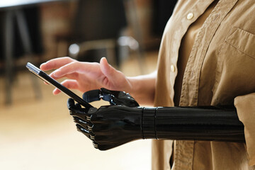 Close-up of girl with prosthetic arm adapting and learning to type a message on her mobile phone