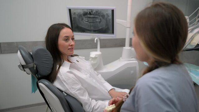 Dentist with a patient looking at a tomographic image of the teeth and discussing a treatment and implantation plan