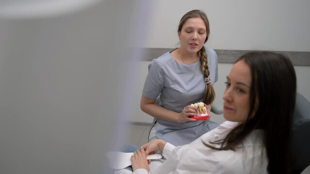 Dentist with a patient looking at a tomographic image of the teeth and discussing a treatment and implantation plan
