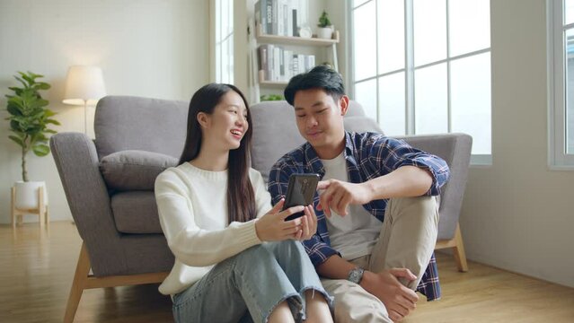 Asian couple man and woman using mobile phone, spend time together at home, Asian couple family lifestyle concept