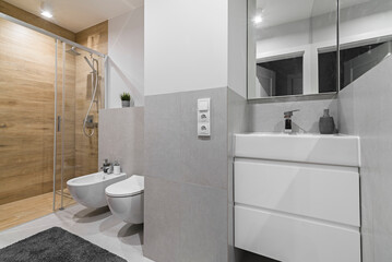 Jasna łazienka w odcieniach szarości i materiałąch drewnopodobnych