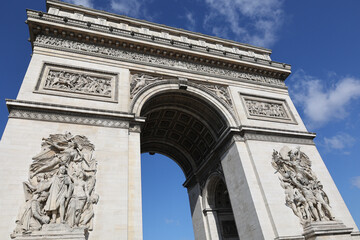 close view of the Arc de triomphe in Paris against blue sky