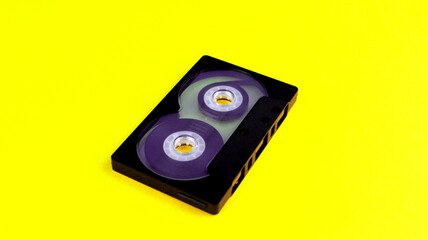 One black audio cassette on a yellow background