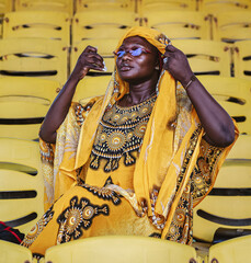 African woman in yellow suit and glasses sitting in an empty grandstand on Independence Square in Accra Ghana West Africa