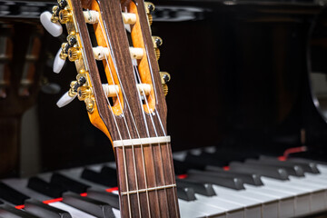 classical guitar against grand piano keys - musical instruments closeup - Spanish guitar with nylon...