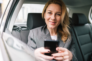A young business woman uses her phone in a car.