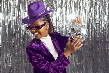 Let's have party. Cheerful young dark-skinned woman with shiny mirror disco ball in her hand on...