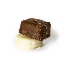 Two candies on top of each other on white background. White chocolate covered piece and dark chocolate sprinkled with salt crystals.