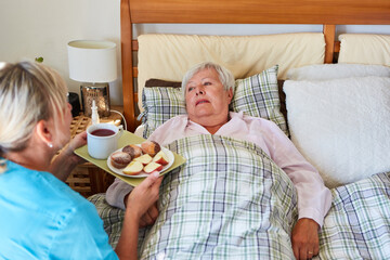 Pflegekraft vom Pflegedienst serviert Frühstück für Seniorin