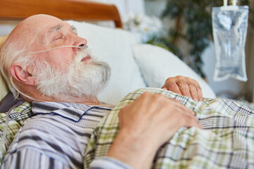 Alter kranker Mann liegt mit Sauerstoffkatheter im Bett