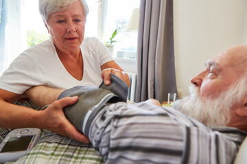 Frau vom Pflegedienst beim Blutdruck messen von Senior
