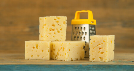 Cheese cubes with miniature grater on a wood kitchen table