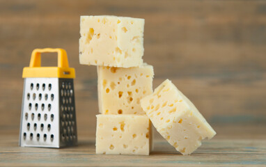Cheese cubes with miniature grater on a wood kitchen table