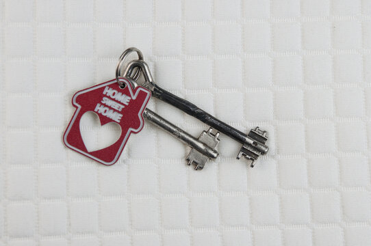House Keys With Red House Key Chain On White Background.