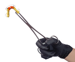 A doctor's hand in a black medical glove holds a colorful children's orthodontic appliance in a clip. The concept of oral hygiene in childhood.